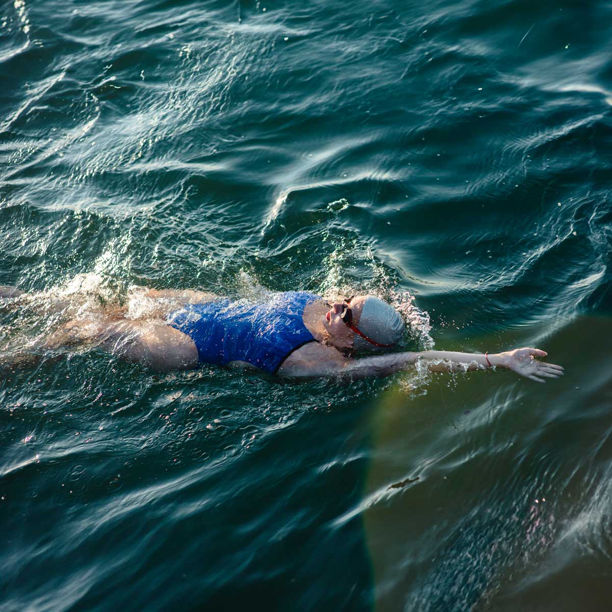A woman swimming confidently in open water, highlighting the importance of physical fitness, endurance, and outdoor activities. Perfect for promoting water sports, swimming, and active, healthy lifestyles.