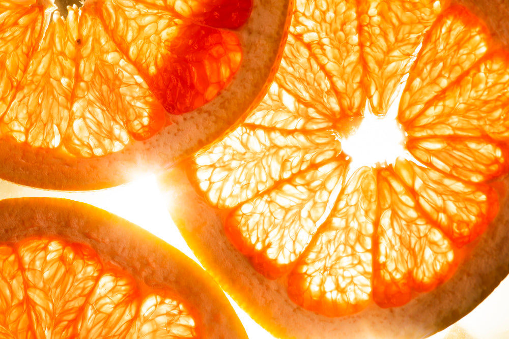 Close-up of orange slices illuminated by sunlight, showcasing the bright, translucent pulp and vibrant orange color of the fruit.